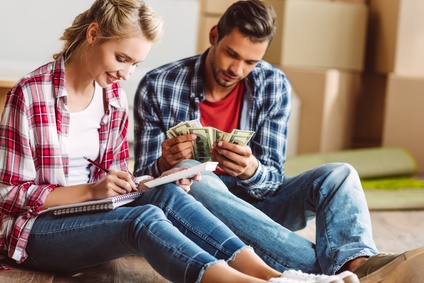 Junges Paar zählt sein Geld, während sie in der neuen Wohnung auf dem Boden sitzen
